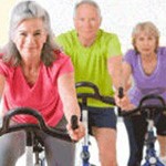 Senior citizens on exercise bikes.
